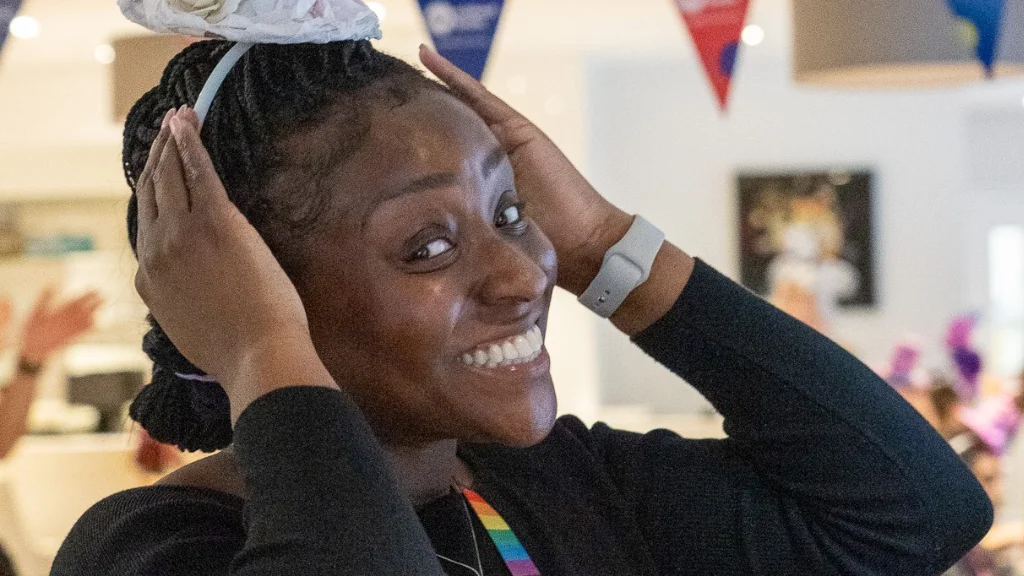 A woman wearing a hat, holding it on her head